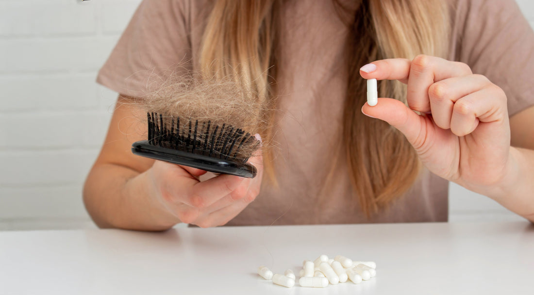 A woman suffering hair loss holds up a biotin tablet.