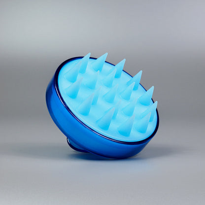 Die Dr. Balwi Massagebürste von Dr. Balwi Shop, eine blaue Silikonbürste für die Kopfmassage, ist auf grauem Hintergrund abgebildet. Ihre runde Form und die weichen Borsten sollen das Haarwachstum fördern und eine entspannende Kopfhautmassage ermöglichen.